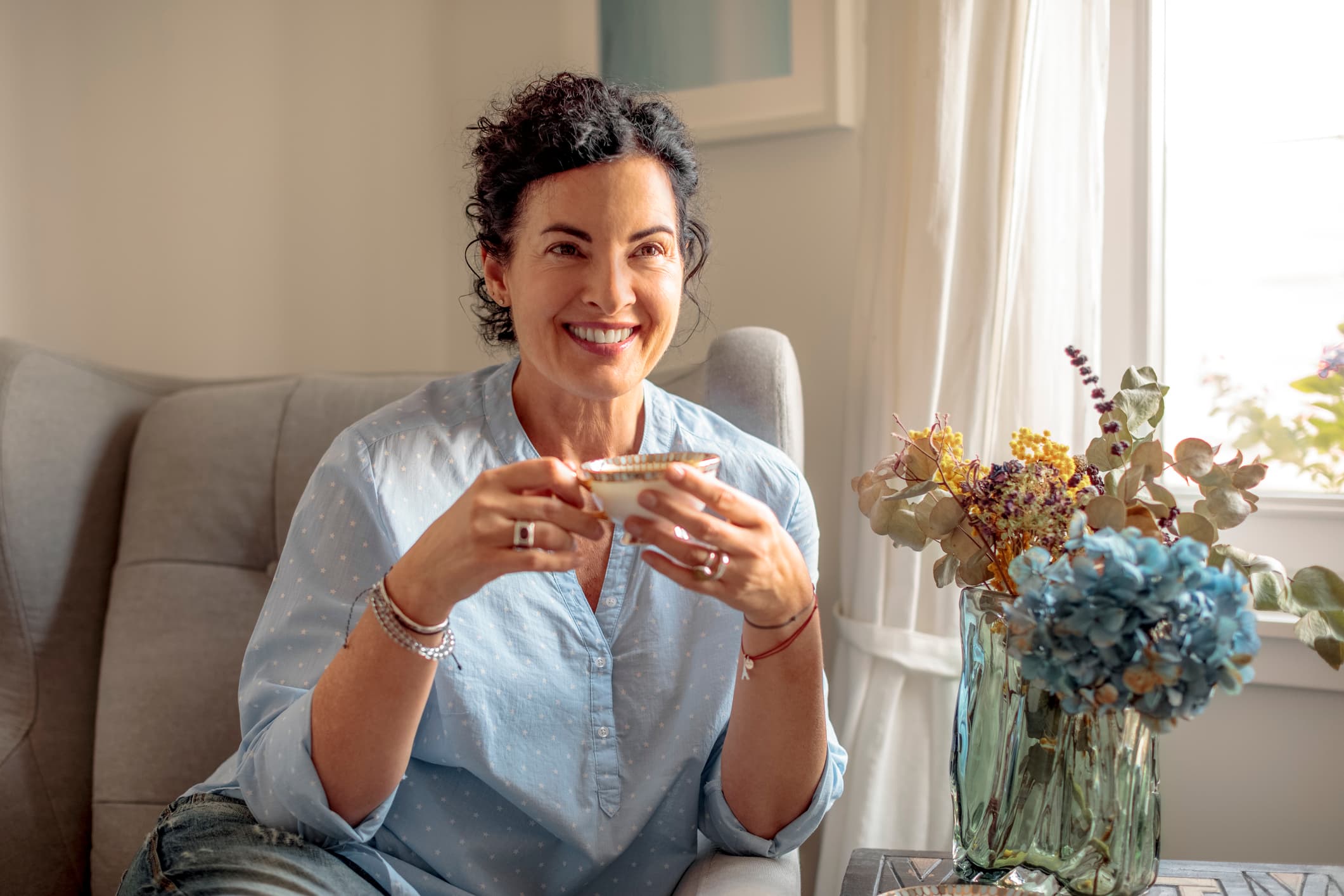 A woman in midlife sitting at home with a cup of tea