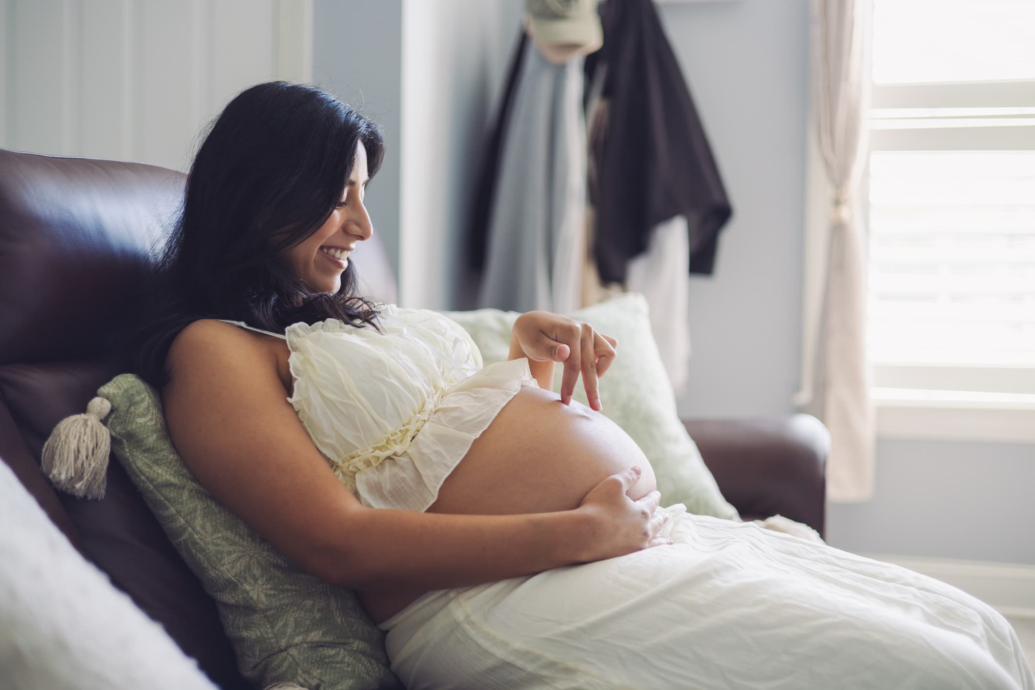 A pregnant woman resting on a couch with a hand on her belly